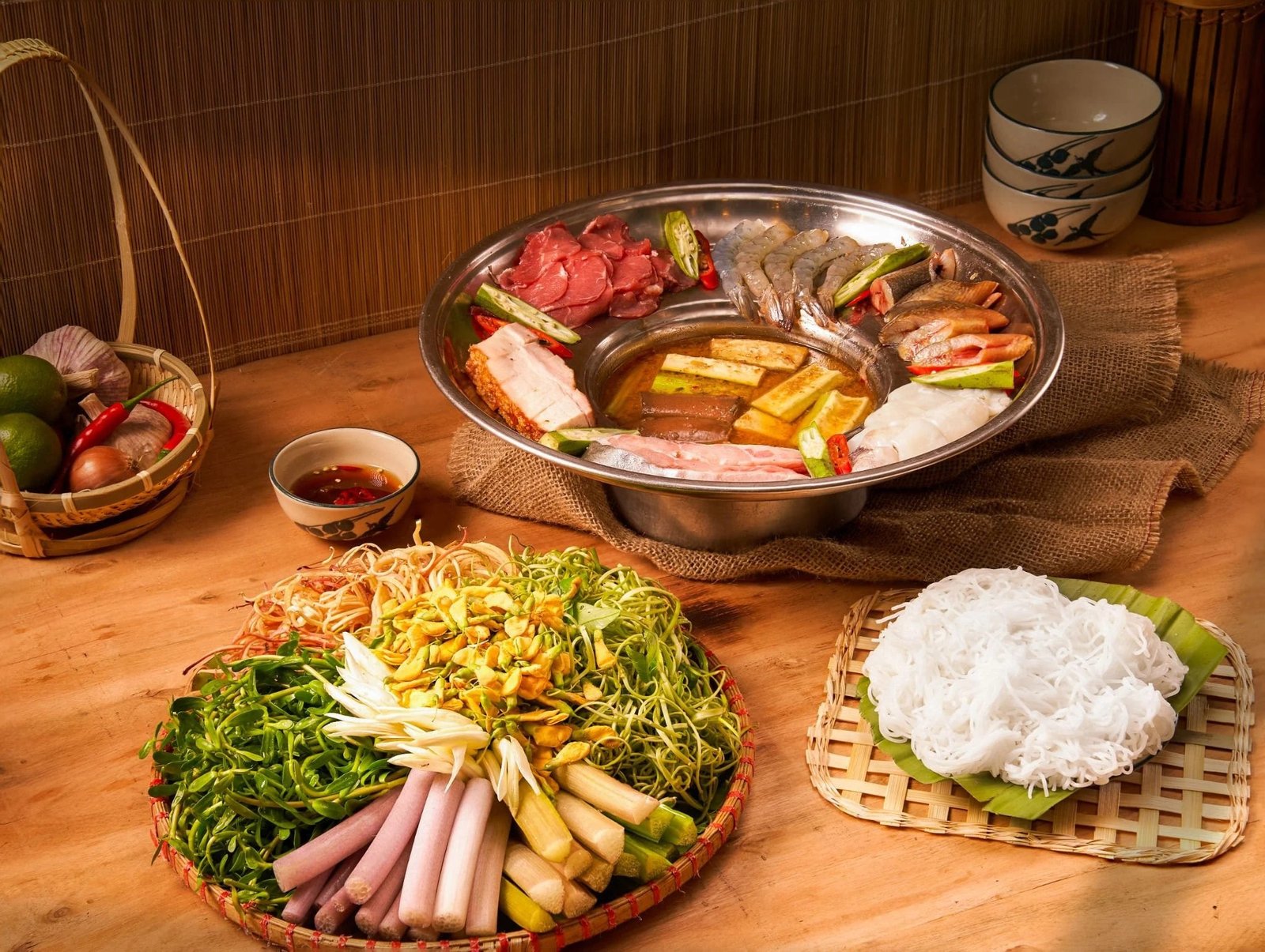 Top Tour Du Lịch Miền Nam Hấp Dẫn Nhất Bạn Không Thể Bỏ Lỡ 2 Lẩu cá truyền thống Việt Nam với be thui, tôm, rau sống, bún tươi, gia vị và nước mắm trên bàn gỗ hướng dẫn ăn lẩu.
