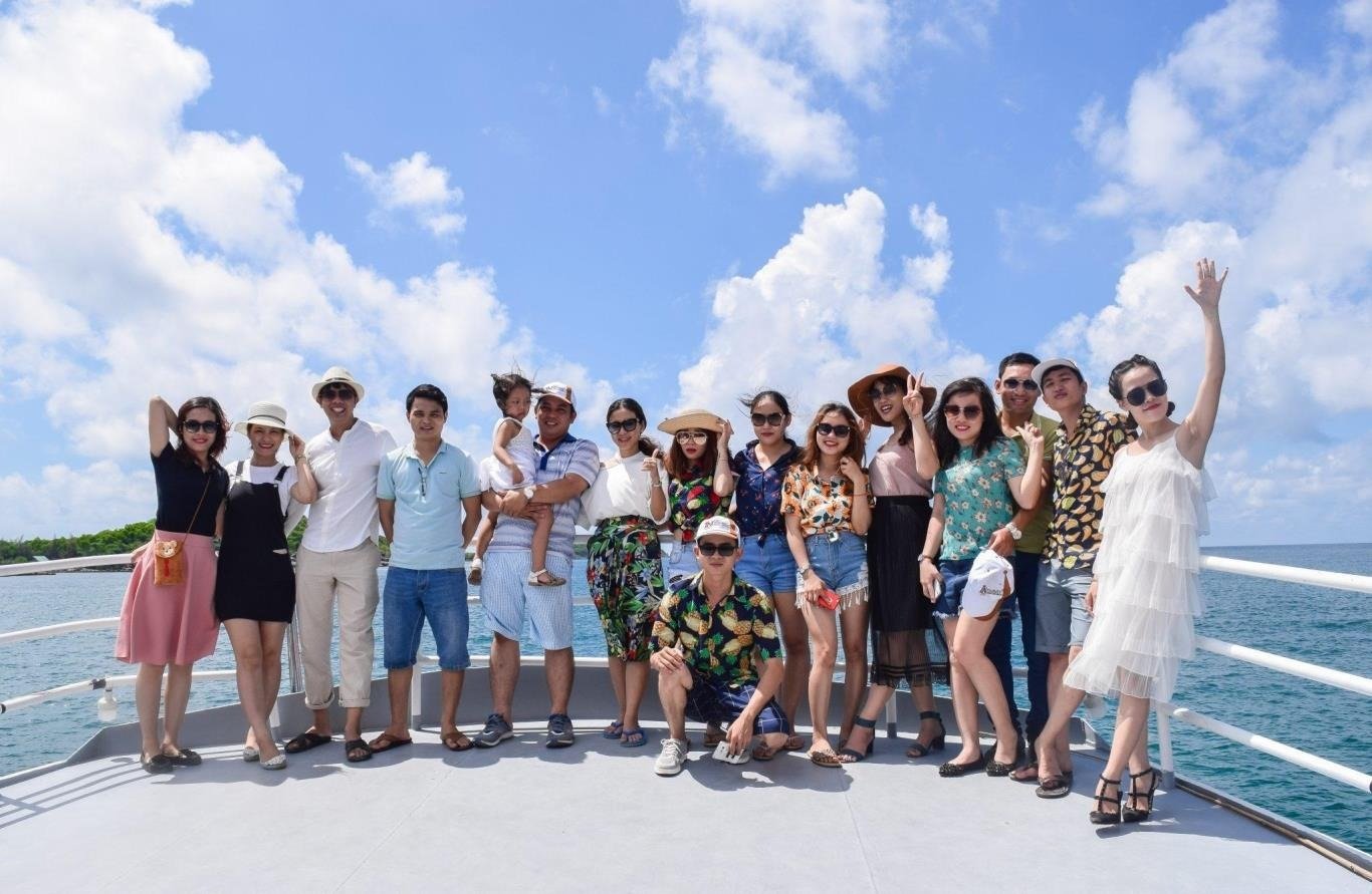 Nhóm người trên du thuyền dưới bầu trời xanh, hòa mình vào không khí vui tươi của chuyến đi biển.