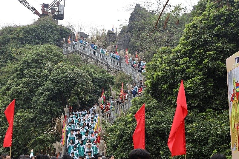 Mô Hình Du Lịch Giải Trí: Xu Hướng Hấp Dẫn Khách Du Lịch Hiện Đại 3 Đoàn người leo bậc thang đá núi lễ hội, cờ đỏ rực, cây xanh bao quanh, tạo khung cảnh lễ hội nhộn nhịp ở Việt Nam.