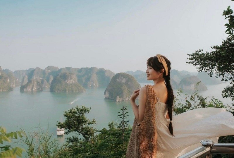 Cô gái đứng trước cảnh biển tuyệt đẹp tại Hạ Long, phía sau là những ngọn núi đá vôi độc đáo nhô lên từ mặt nước xanh.