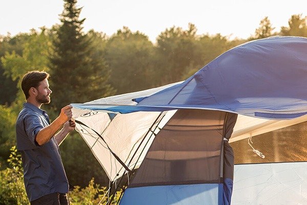 Mẹo Dựng Lều Nhanh Chóng Khi Đi Trekking: Hướng Dẫn Chi Tiết 3 Người đàn ông đang dựng lều màu xanh ngoài trời, giữa khung cảnh rừng núi vào lúc hoàng hôn.