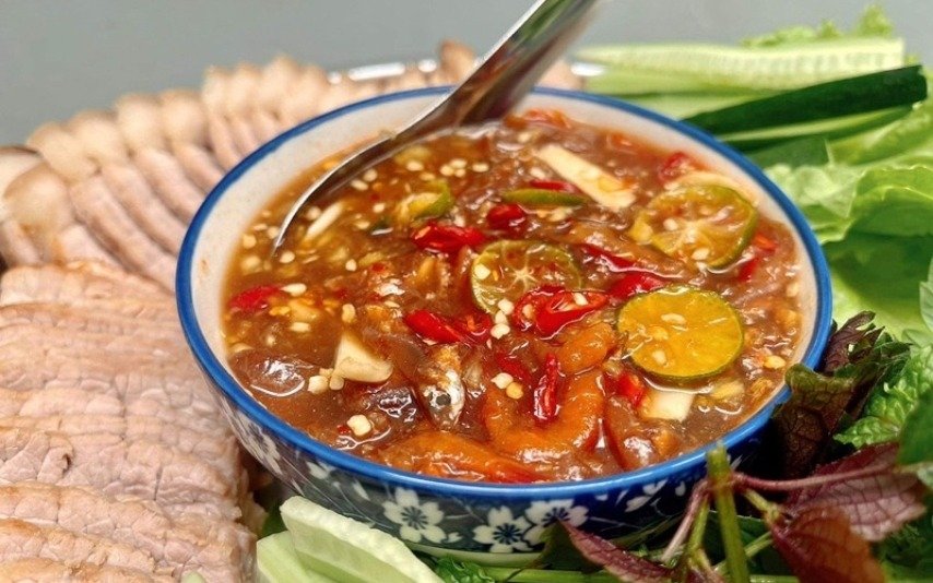 Bát mắm nêm truyền thống ngon mắt với ớt, tắc, tỏi, cùng thịt heo luộc và rau sống tươi ngon, sẵn sàng thưởng thức.