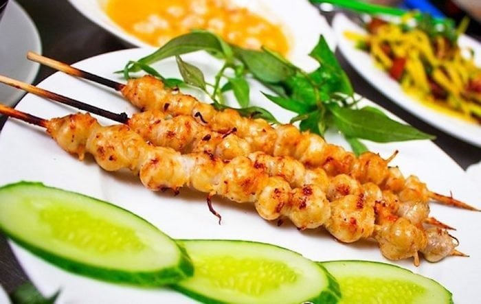 Các xiên tôm nướng vàng ngon lành, kèm theo lát dưa leo tươi và rau thơm, tạo nên một bữa ăn hấp dẫn trên đĩa trắng.