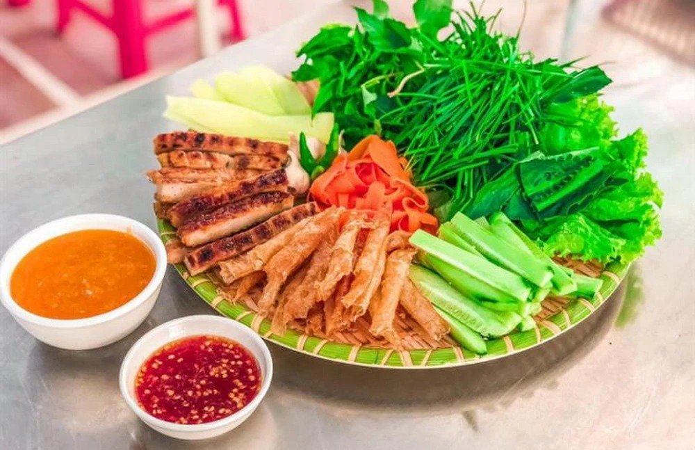 Món ăn Việt đầy đủ sắc màu, gồm thịt nướng, nem rán, rau sống tươi xanh và sốt chấm, bày biện tinh tế trên đĩa.