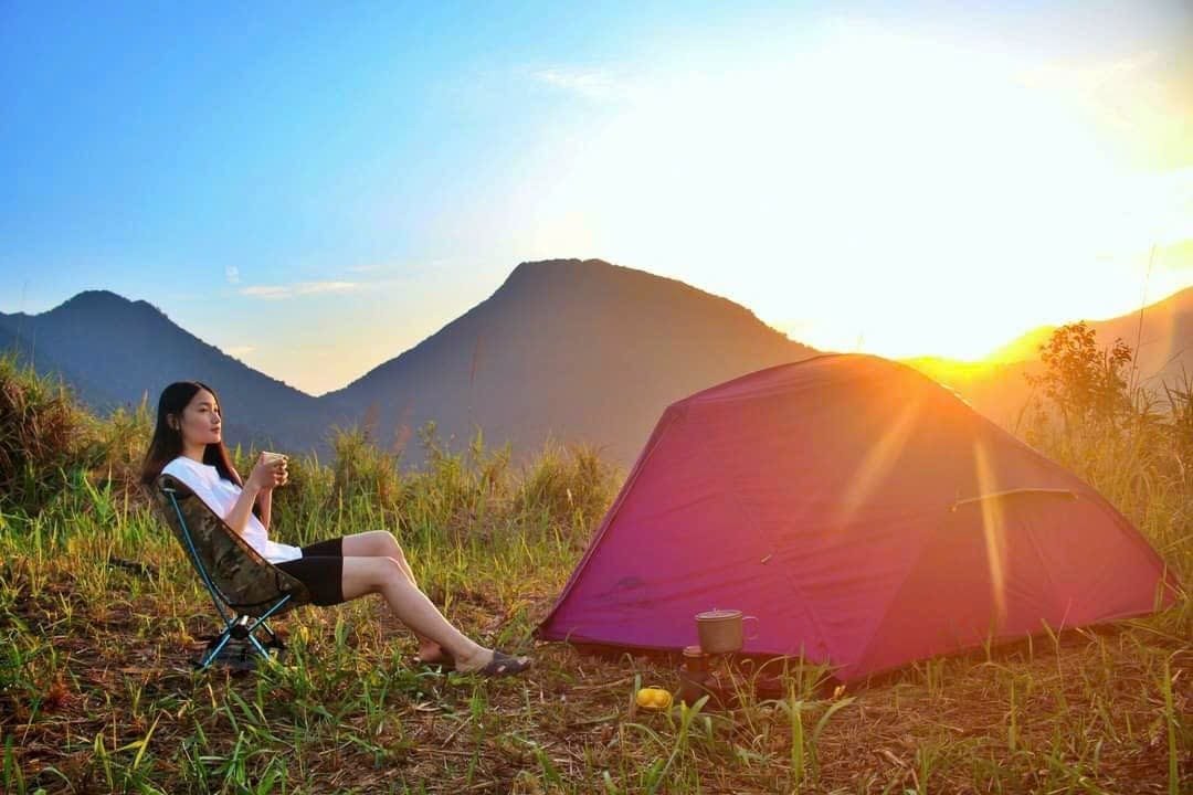 Top Những Tour Trekking Đón Bình Minh Trên Núi Tuyệt Đẹp Bạn Không Thể Bỏ Lỡ 2 Người phụ nữ thưởng thức cốc nước khi cắm trại giữa thiên nhiên, ngay bên lều tại hoàng hôn dưới ánh mặt trời.
