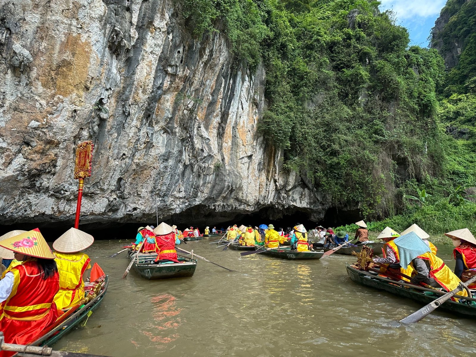 Khám phá cảnh quan ngoạn mục của Ninh Bình, thuyền chèo vào hang động với những vách đá hùng vĩ và cây cối xanh mướt.