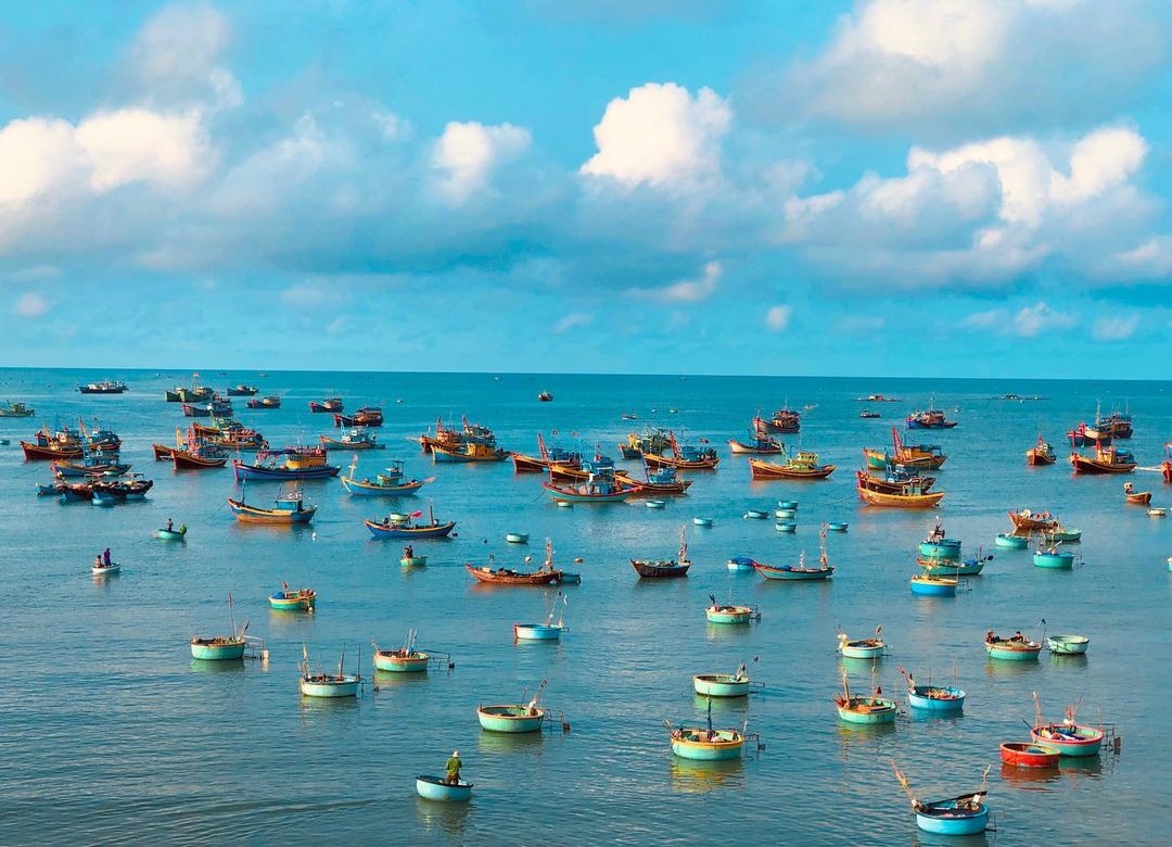 Biển xanh với bầu trời trong và tàu thuyền đánh cá tấp nập, khung cảnh yên bình ngày đánh bắt ở vùng biển.