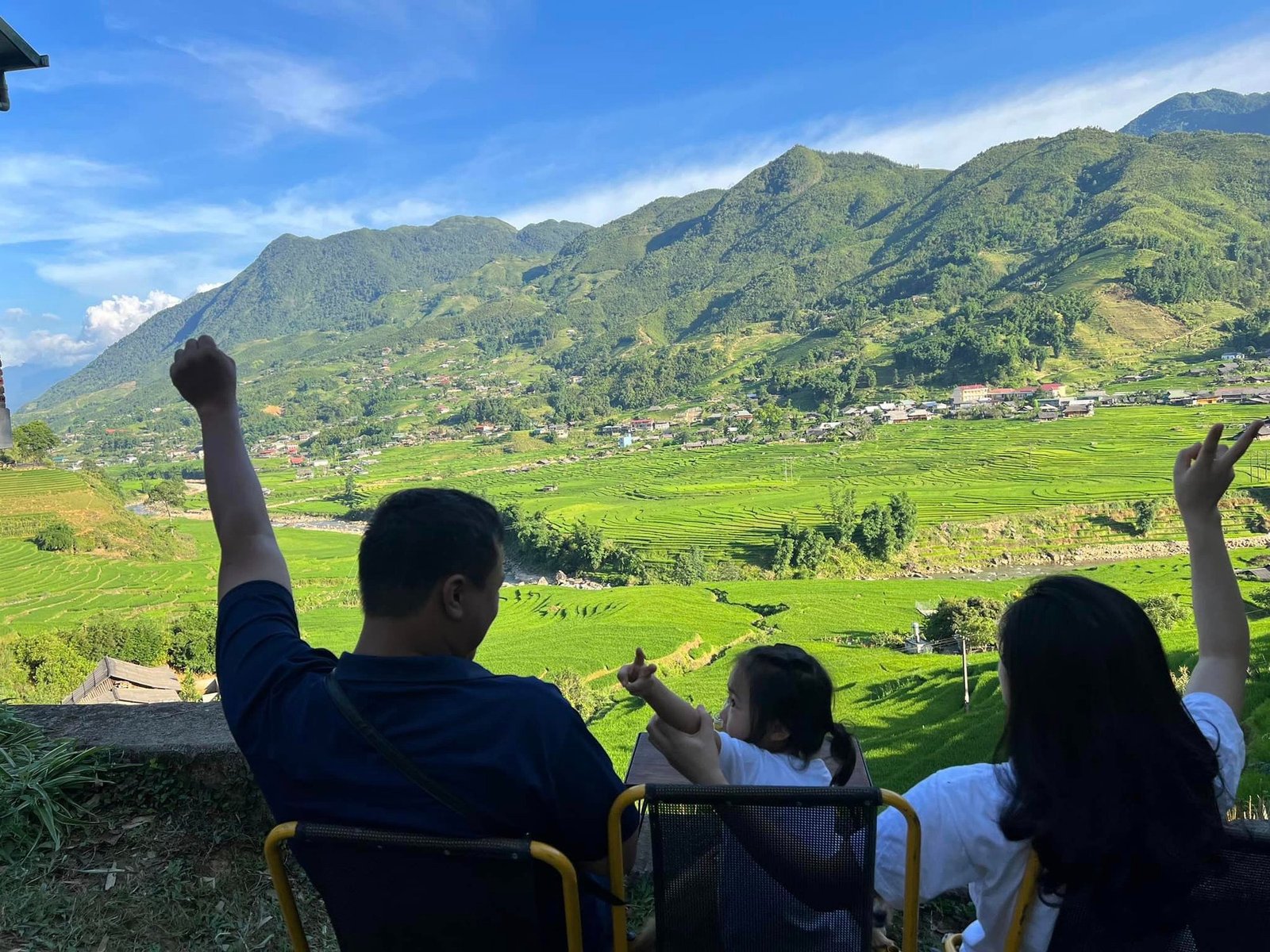 Gia đình thư giãn ngắm nhìn thung lũng xanh mướt cùng ruộng bậc thang và núi non tại một vùng quê Việt Nam tuyệt đẹp.