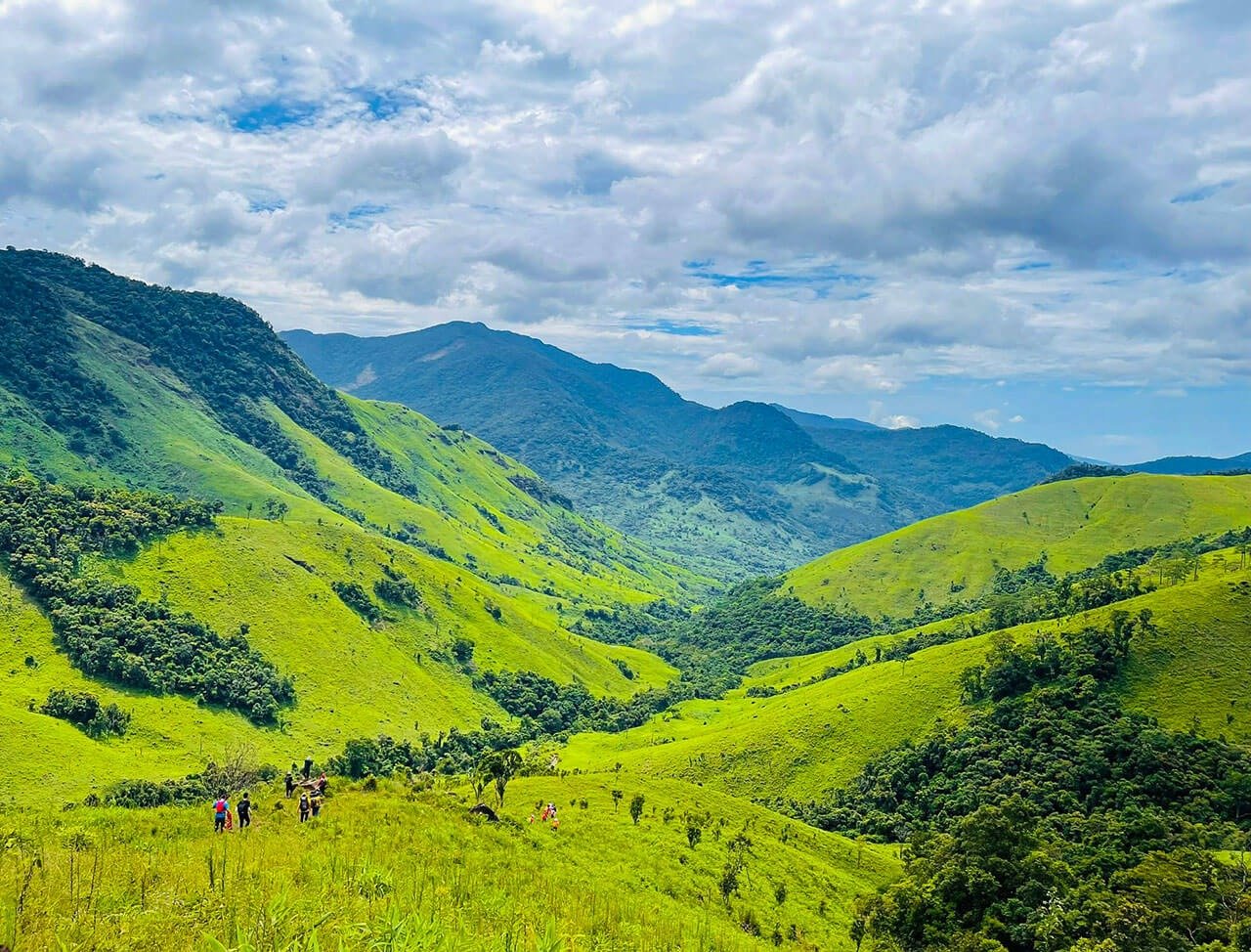Phong cảnh núi non xanh rì, thung lũng tươi mát dưới bầu trời mây trắng, nhóm người leo núi trong khung cảnh tự nhiên.