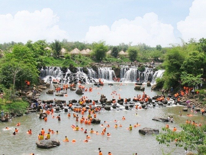 Du khách tắm suối dưới thác nước giữa thiên nhiên xanh tươi, nước trong và mát lạnh, không khí tươi mát.