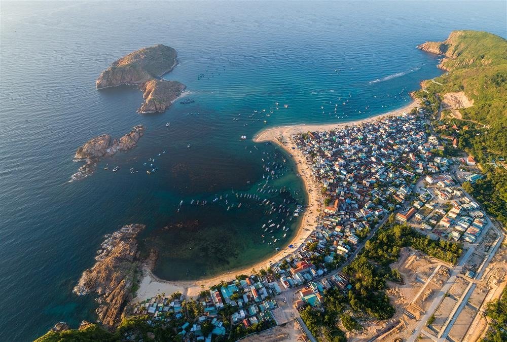 Toàn cảnh làng chài bên bờ biển xanh, với bãi cát trắng và những hòn đảo nhỏ, tạo nên cảnh quan thơ mộng.