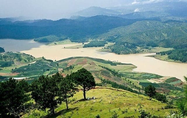 Quang cảnh núi non và hồ nước tại Đà Lạt, với cây xanh và đất đồi trải dài, tạo khung cảnh thiên nhiên hùng vĩ.