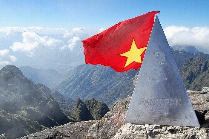 Top Tour Du Lịch Hè 2024 Hấp Dẫn Không Thể Bỏ Lỡ 3 Cột mốc kim loại đánh dấu đỉnh Fansipan, cao 3,143m với lá cờ Việt Nam bay phấp phới bên cảnh núi rừng hùng vĩ.