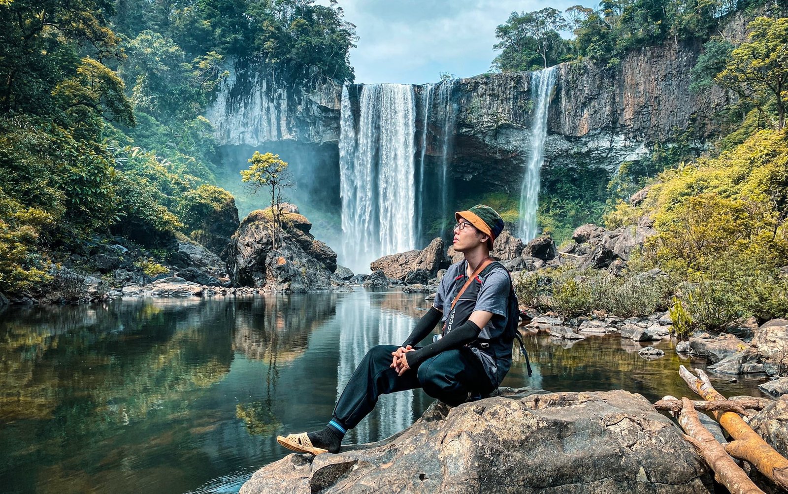 Du khách ngồi bên thác nước thiên nhiên giữa rừng nhiệt đới, thư giãn và ngắm cảnh trong bầu không khí tươi mát.