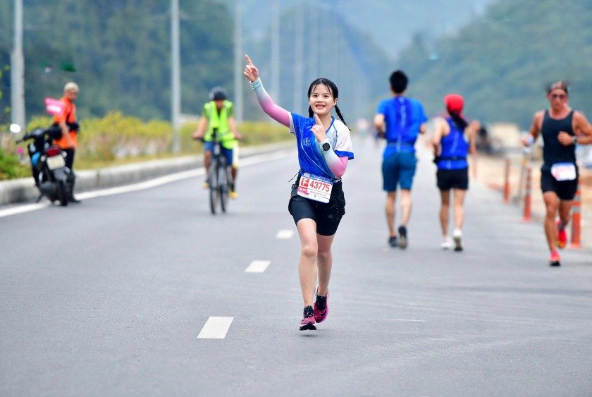 Du Lịch Thể Thao: Lựa Chọn Hoàn Hảo Cho Các Tín Đồ Đam Mê Xê Dịch 3 Người phụ nữ trẻ chạy bộ trong trang phục thể thao xanh, giơ tay tạo dáng chiến thắng trên đường đua.