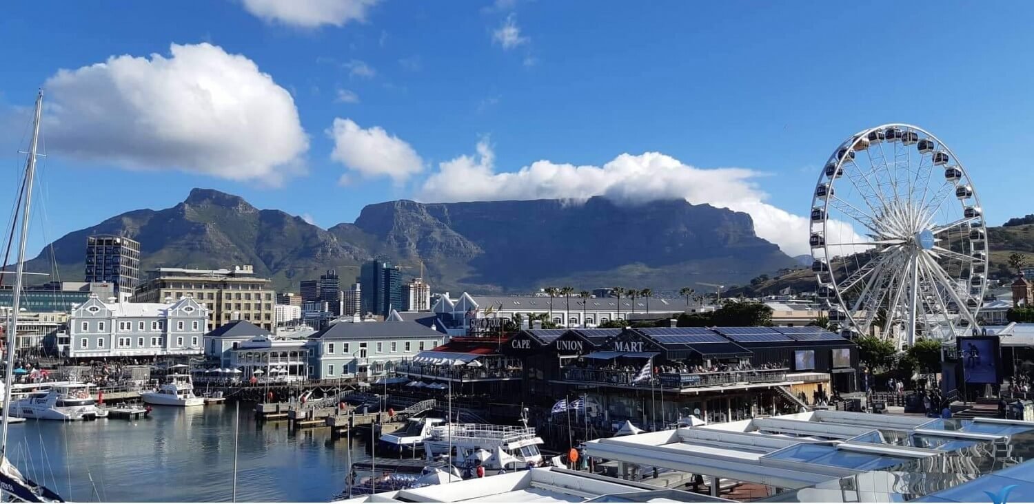Khung cảnh bến cảng V&A Waterfront tại Cape Town với bánh xe Ferris và dãy núi Table Mountain phía sau.
