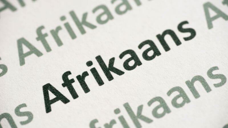 Từ Afrikaans in đậm phóng to trên trang giấy trắng, nhấn mạnh ngôn ngữ Nam Phi gốc Hà Lan.