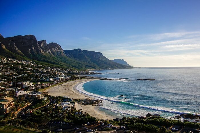 Bờ biển Cape Town tuyệt đẹp với cát trắng mịn, biển xanh trong và dãy núi hùng vĩ dưới bầu trời xanh.